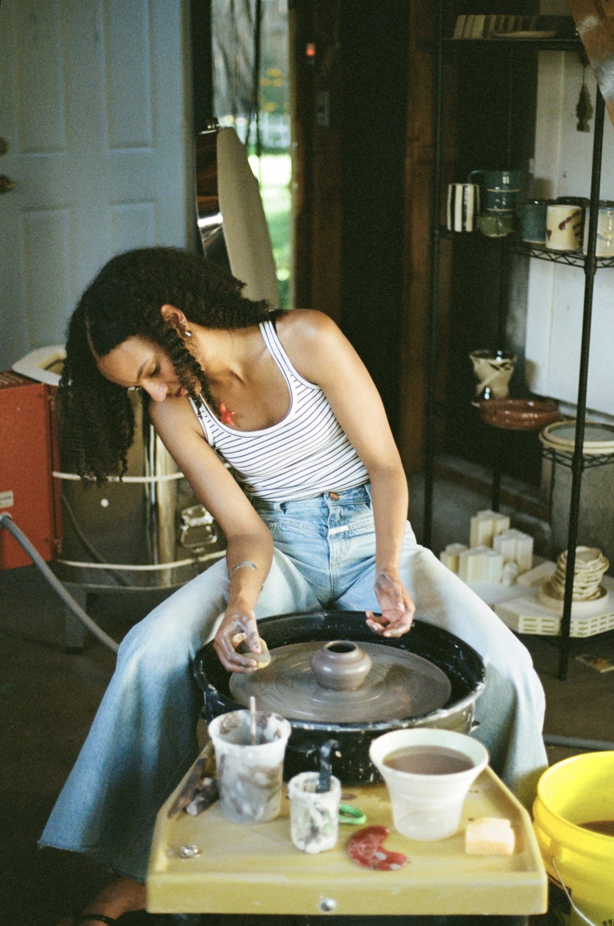 Maeleisa shaping a piece at the pottery wheel