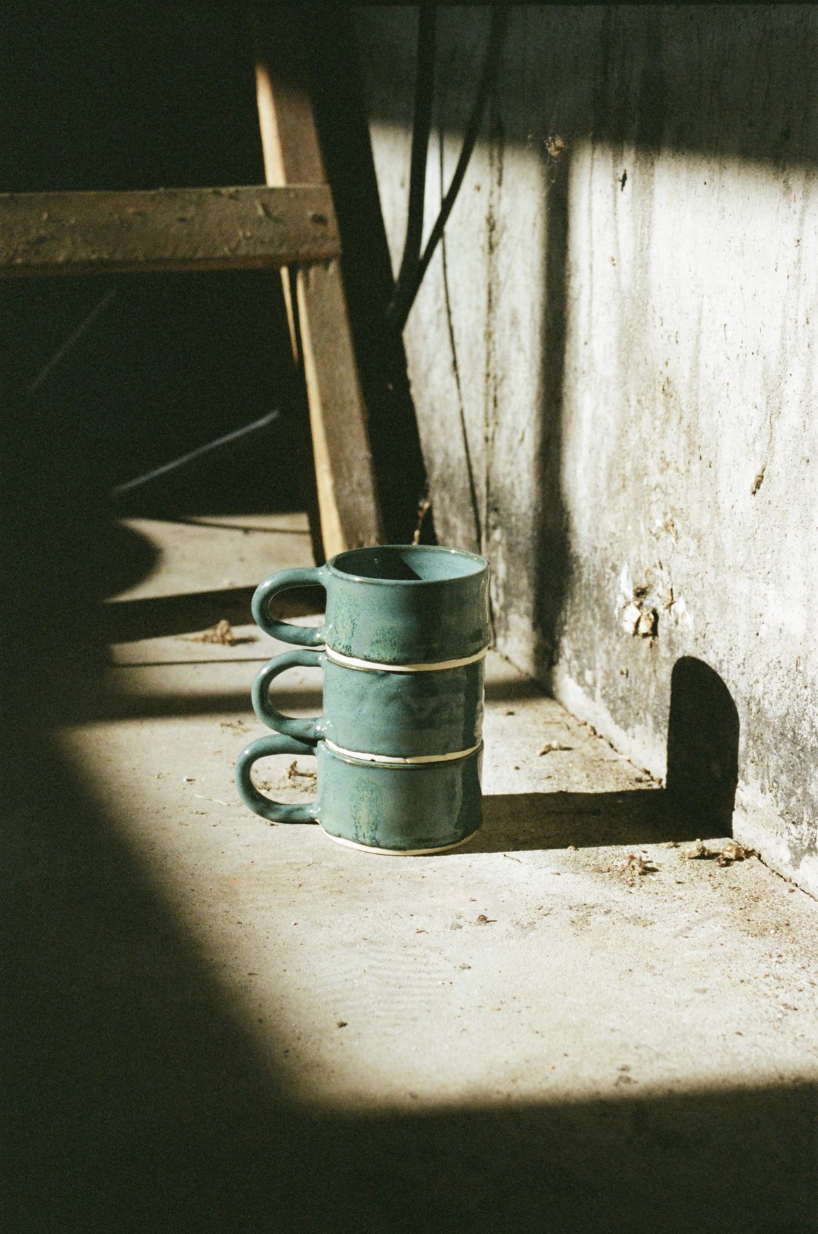 A stack of teal handmade mugs