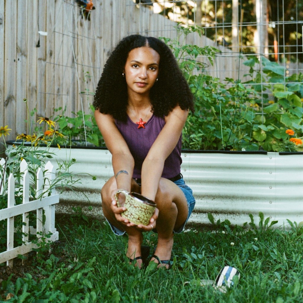 Maeleisa holding a speckled mug in the garden